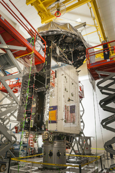 An exposed satellite is suspended in the middle of a cleanroom at NASA